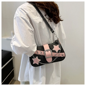 Detail of black denim underarm bag with pink star patch and silver chain on model