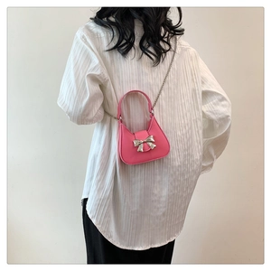Vue détaillée d'un mini sac à main rose avec noeud argenté et chaîne sur chemise blanche