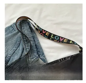 Detail einer schwarzen Canvas-Tragetasche mit breitem buntem LOVE-Stickerei-Gurt
