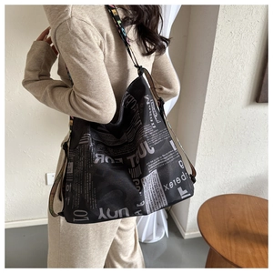 Detail of black canvas tote with newspaper print and colorful bohemian shoulder strap