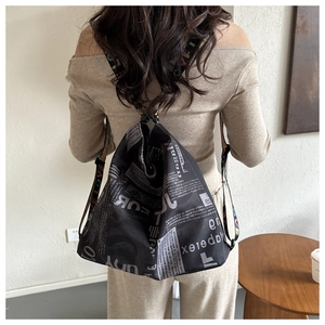 Detail of a black canvas backpack with newspaper print and colorful LOVE shoulder straps