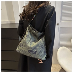 On-body view of large canvas bucket bag with vintage print and lettered wide strap