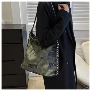 Detail of army green bucket bag with vintage newspaper print and colorful LOVE strap