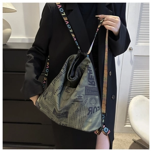 Close-up of newspaper print tote bag featuring a colorful LOVE letter woven strap
