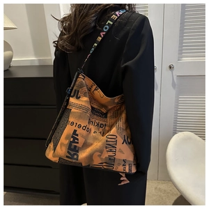 Detail of vintage newspaper print hobo bag with embroidered love strap on black blazer