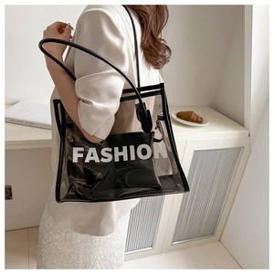 Detail view of transparent PVC tote bag with Fashion lettering and black leather straps