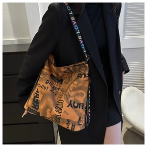 Detail der Vintage-Tote-Bag mit Zeitungsdruck und buntem LOVE-Buchstaben-Schultergurt