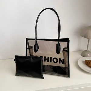 Detail of transparent PVC tote bag with black inner pouch and Fashion lettering