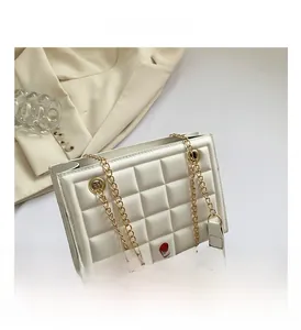 Détail du sac crème matelassé avec chaîne dorée et large bandoulière en cuir bicolore