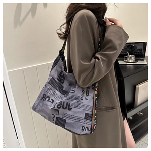 Detail of newspaper print tote bag with colorful LOVE jacquard shoulder strap