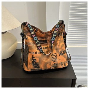 Detail of orange canvas tote bag featuring black newspaper print and colorful LOVE straps