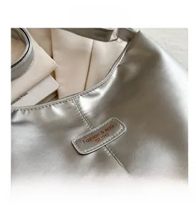 Close-up of silver pleated tote bag with metallic mirror finish and fashion logo patch