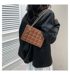 Détail du sac à bandoulière matelassé marron avec chaîne dorée porté par un mannequin