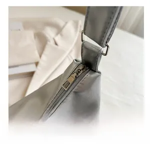 Detailed macro shot of smooth metal zipper and D-ring on silver faux leather tote bag