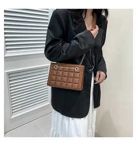 Détail d'un sac à bandoulière matelassé marron avec une élégante chaîne dorée