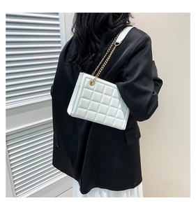 Détail du sac matelassé blanc avec bandoulière en chaîne dorée sur un mannequin