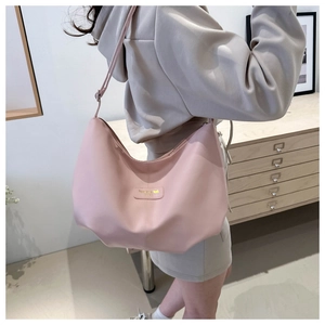 Détail du sac demi-lune en nylon rose montrant la bandoulière et le petit logo devant