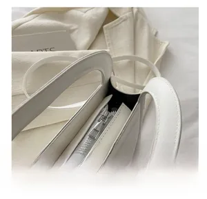 Close-up of smooth silver metal zipper and precise stitching on white leather bag