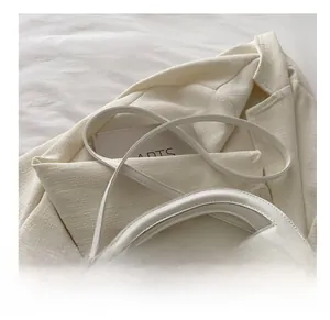 Close-up of white crossbody bag strap and textured leather with logo detail
