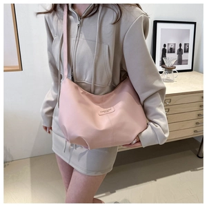 Détail d'un sac hobo rose avec coutures et étiquette de mode porté par un mannequin