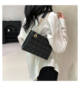 Détail du sac matelassé noir avec chaîne dorée porté à l'épaule pour un style sophistiqué