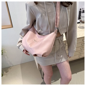 Vue détaillée d'un sac demi-lune rose avec texture souple et bandoulière large réglable