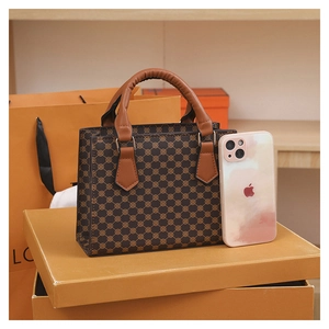 Detail of vintage patterned tote bag with leather handle compared to iPhone for size