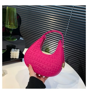 Dettaglio della borsa a mezzaluna rosso rosa con stampa coccodrillo e fibbia dorata