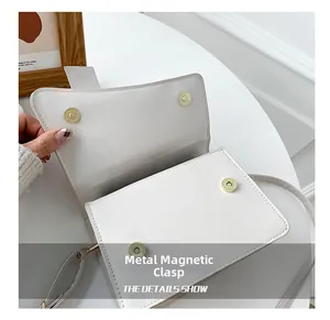 Dettaglio della chiusura magnetica in metallo su una borsa a mano bianca minimalista