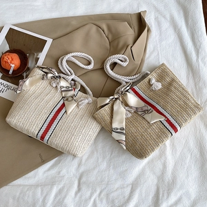 Detail of colorful woven straw tote bags with cotton rope handles and floral silk scarves