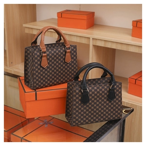 Detail of vintage monogram tote bags in black and brown leather on luxury orange shelves