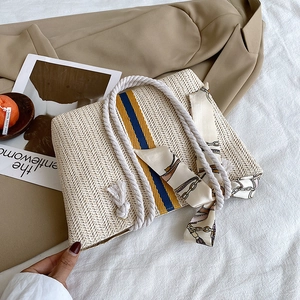 Detail of a woven straw tote with colorful stripes and decorative silk scarf handle
