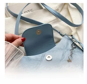 Détail du sac bandoulière bleu clair avec fermoir magnétique et chaîne florale