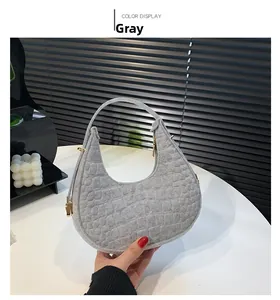 Detail shot of the grey crescent bag featuring crocodile embossed texture and gold zipper