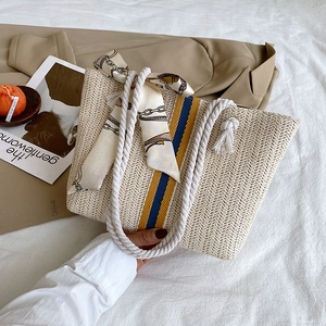 Detail of cream straw tote bag featuring blue-yellow stripes and cotton rope handles