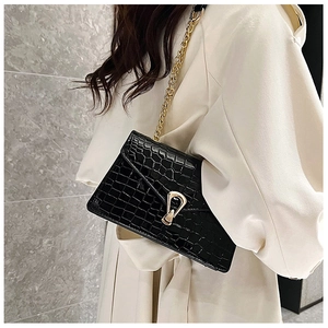 Detail of black crocodile embossed shoulder bag with golden chain and geometric buckle