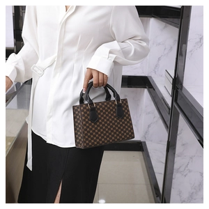 Detail of vintage plaid handbag with black rounded handle and gold metal hardware