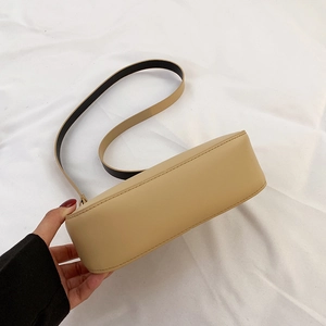 Dettaglio della texture liscia in pelle kaki e della curva inferiore della borsa a spalla
