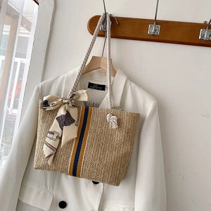 Detailed shot of striped straw tote with cotton rope handles and a decorative silk scarf