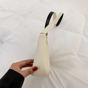Vista laterale della borsa baguette beige con cuciture sottili e tracolla minimalista