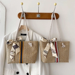 Detail of colorful striped woven straw tote bag featuring white cotton rope handles
