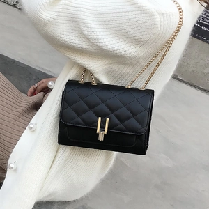 Close-up of black quilted crossbody bag featuring a gold H-shaped buckle and metal chain