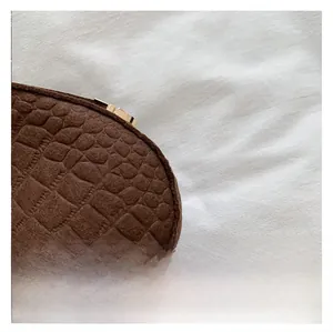 Detailed close-up of dark brown crocodile texture leather and golden metal zipper