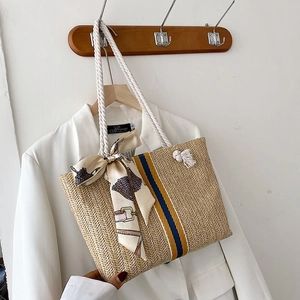 Detail of woven straw tote bag featuring blue-yellow stripes and cotton rope handles