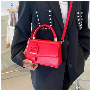 Dettaglio borsa in pelle rossa con fibbia quadrata e accenti in metallo dorato
