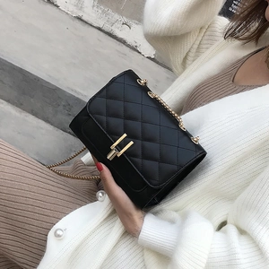 Detail of black quilted leather shoulder bag with gold clasp and chain strap