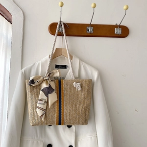 Detailed texture of straw beach tote with cotton rope handles and decorative scarf