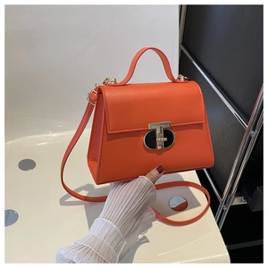 Detail of orange crossbody bag featuring golden T-lock and smooth leather texture