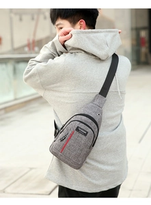 Grey Oxford chest bag with earphone port and red vertical stripe detail shown on model