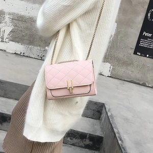 Side view of pink quilted chain bag worn by model against neutral cement background